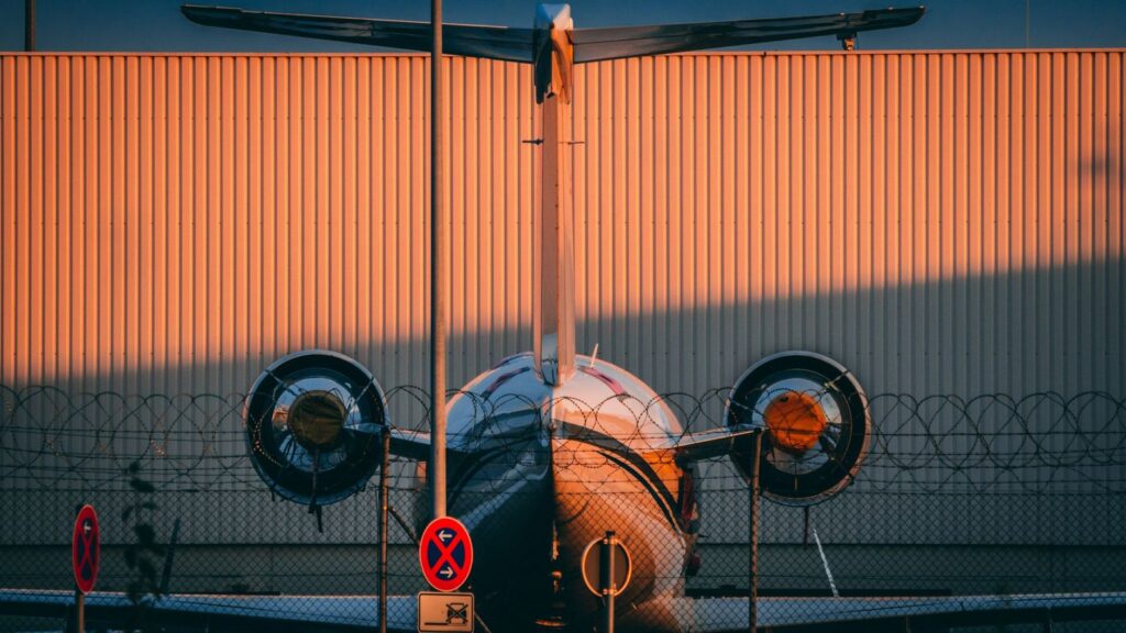 Twin-engine jet aircraft on airport tarmac at sunset.
