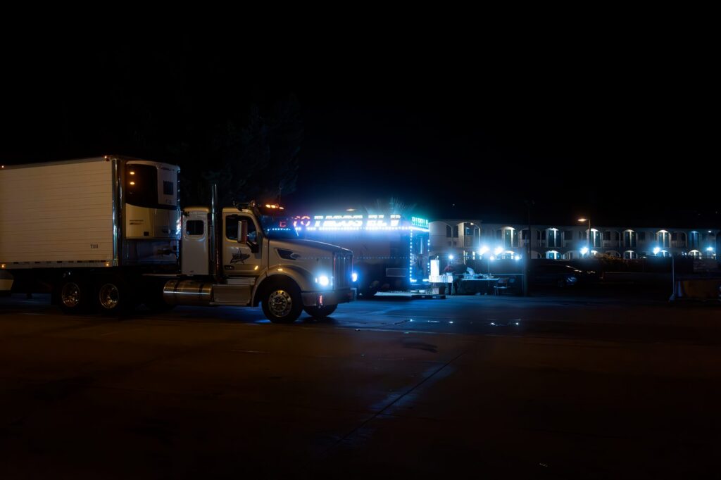 Two illuminated commercial trucks parked on an urban street at night.