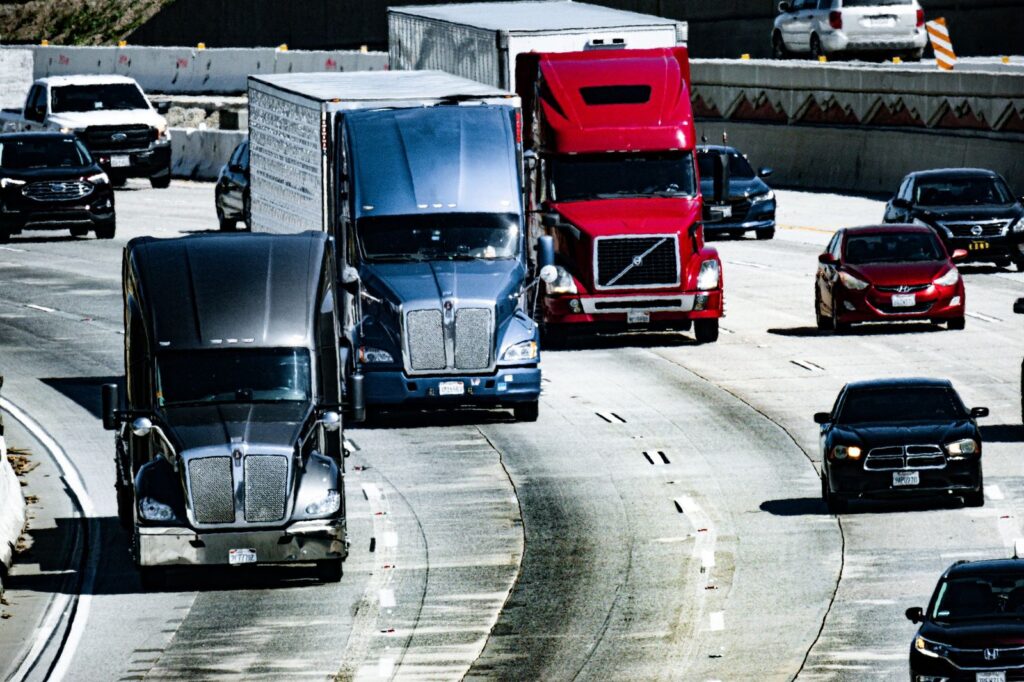 Varios camiones y autos circulando en una autopista congestionada de la ciudad durante el día.