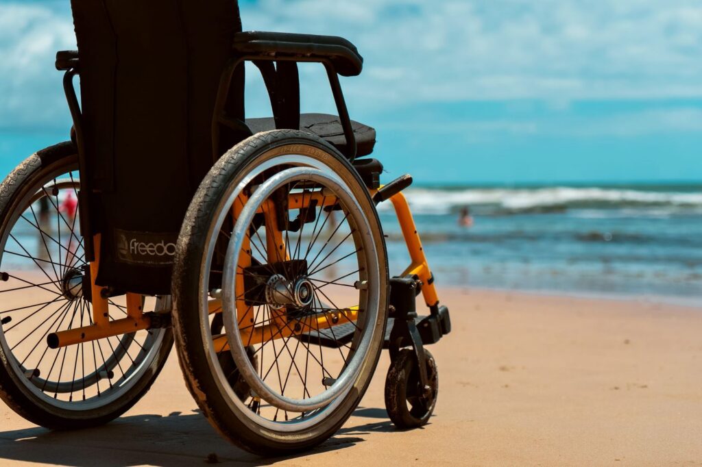 Wheelchair on sandy beach with ocean waves in background.