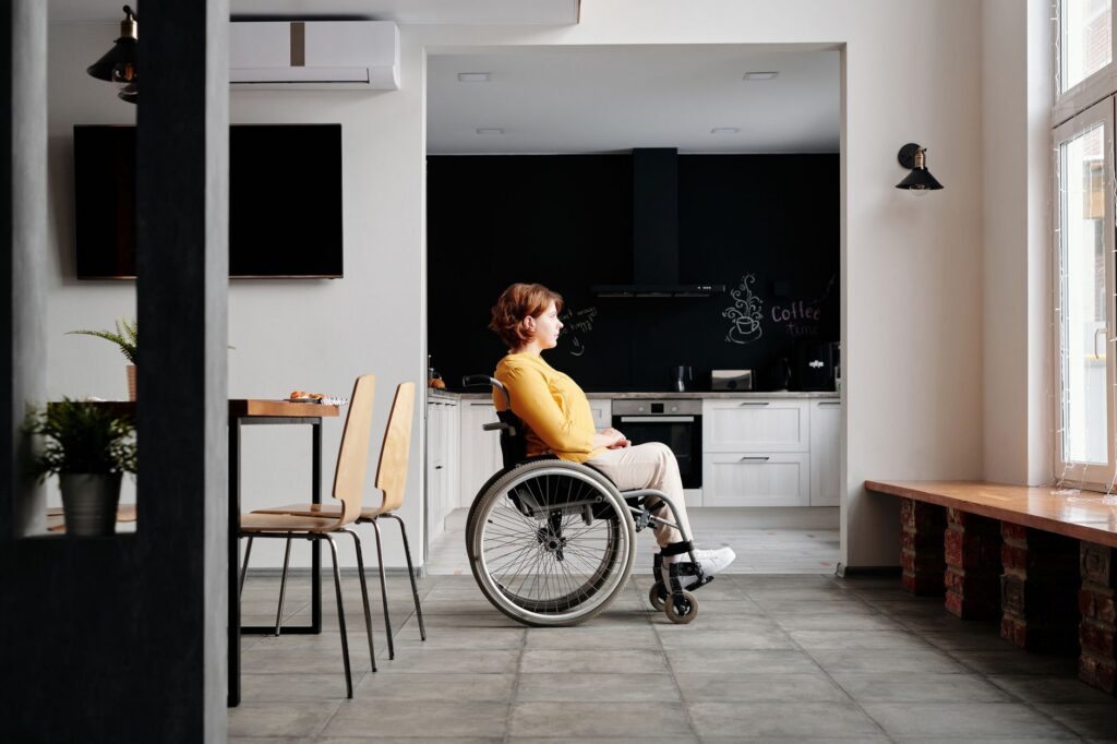 Woman in a wheelchair looking out a window in a modern, accessible home.