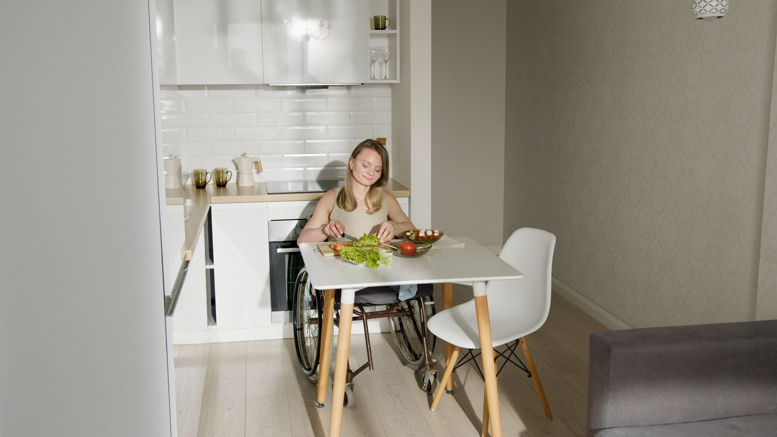 Woman in wheelchair preparing a salad in a modern kitchen.