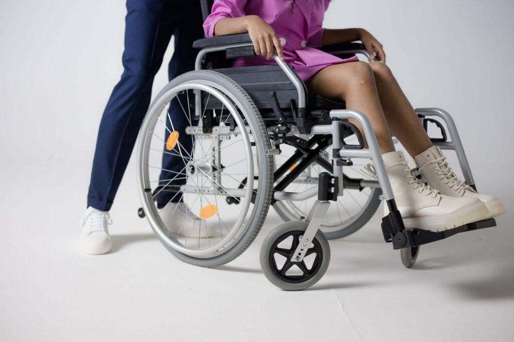 Woman in wheelchair wearing pink outfit, representing disability and accessibility.