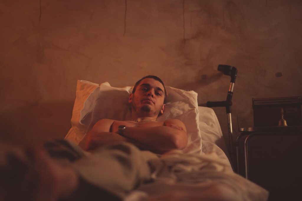 Young man using crutches while resting in bed during recovery.