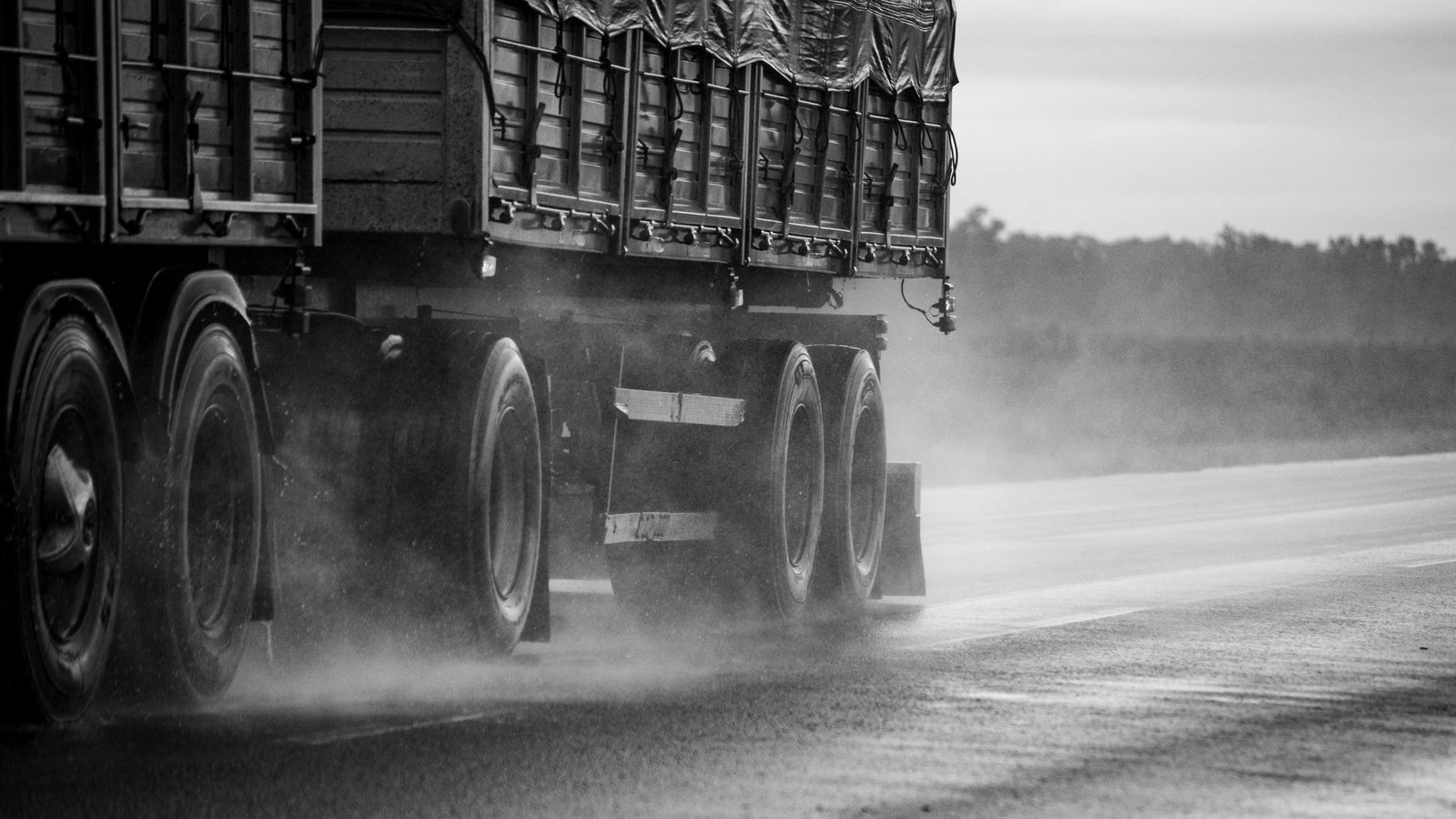 Camión conduciendo en carretera mojada bajo lluvia.