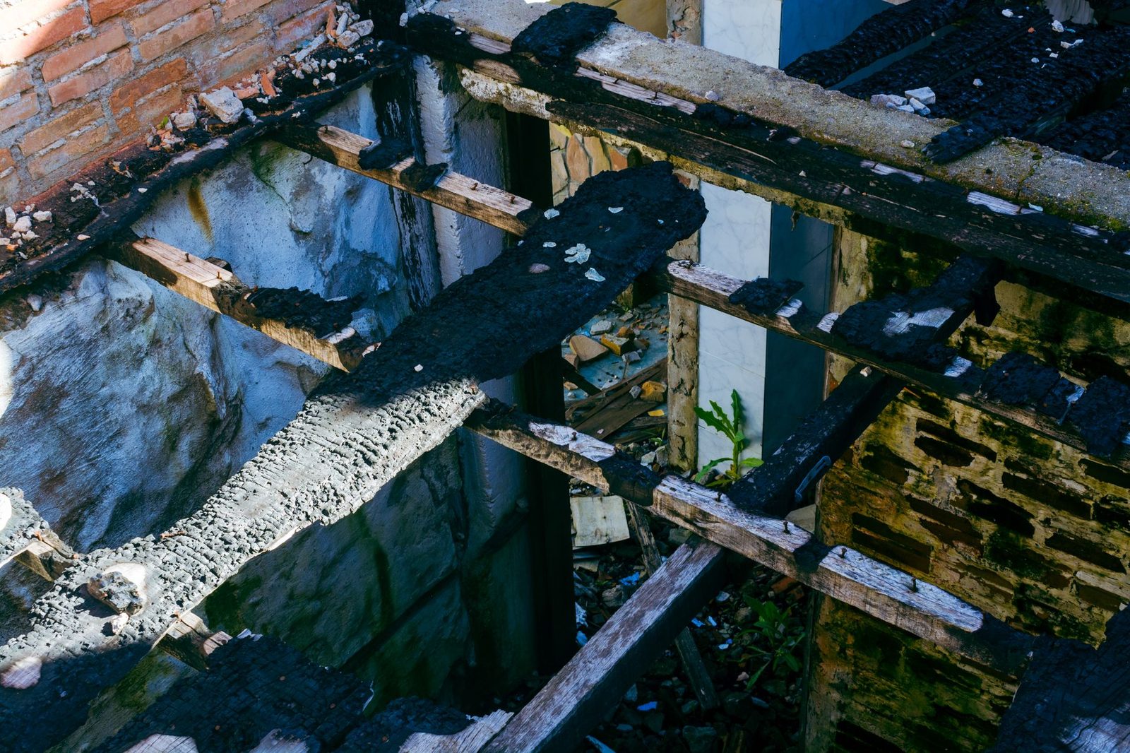 Charred wooden beams in an abandoned, fire-damaged building interior.