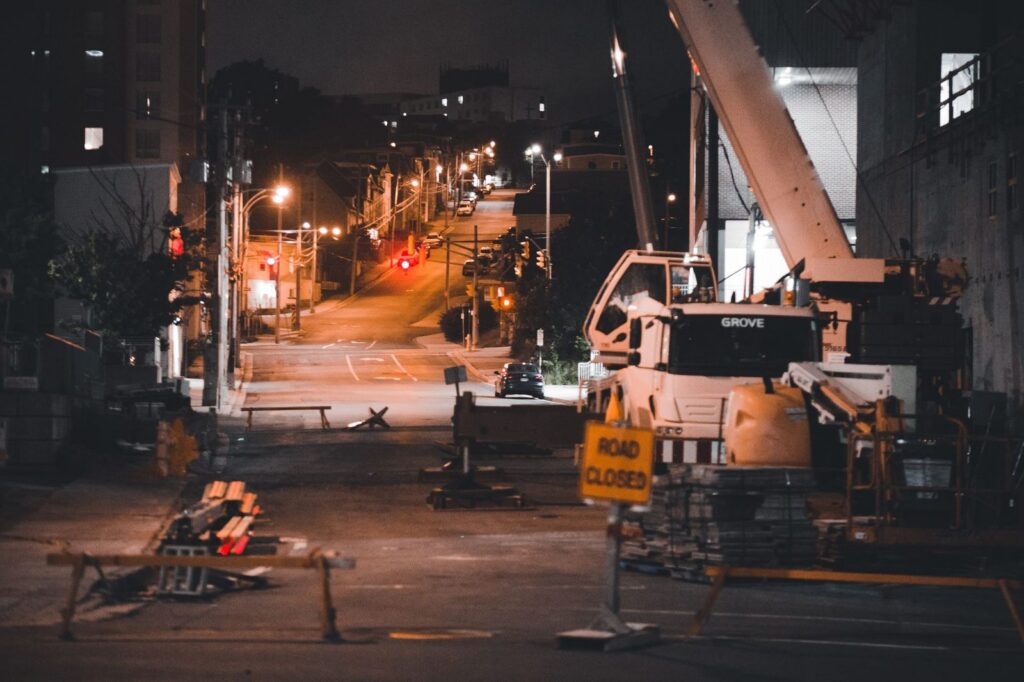 Construction equipment and road closed sign on a city street at night.