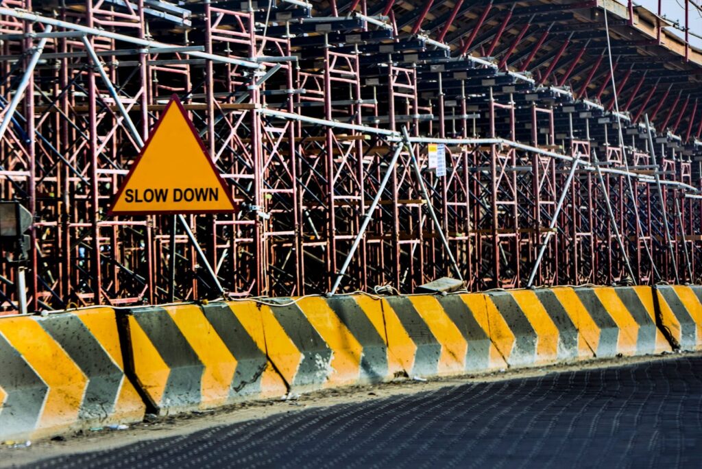 Construction site with &amp;quot;Slow Down&amp;quot; warning sign and scaffolding in Kuwait.