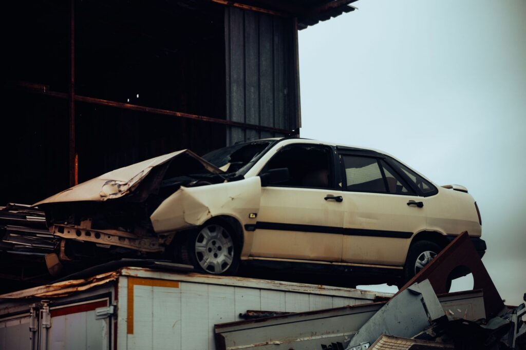 Damaged car on metal scrap heap after total loss.