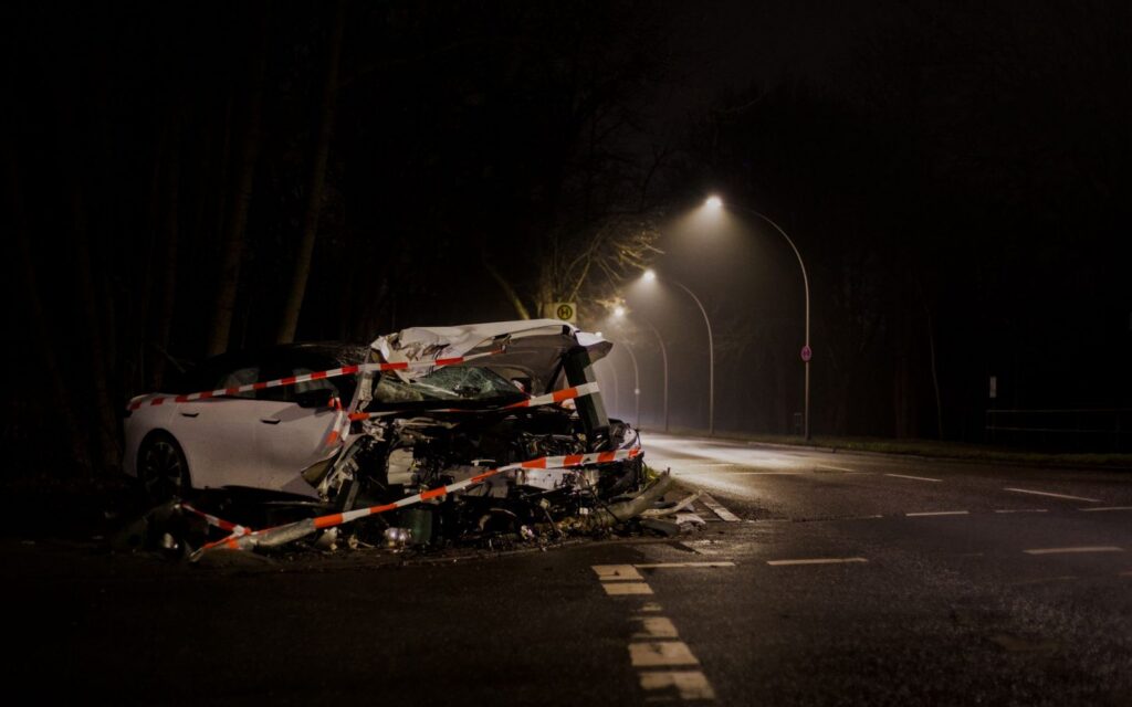 Damaged car wreckage on a dark street at night after collision.