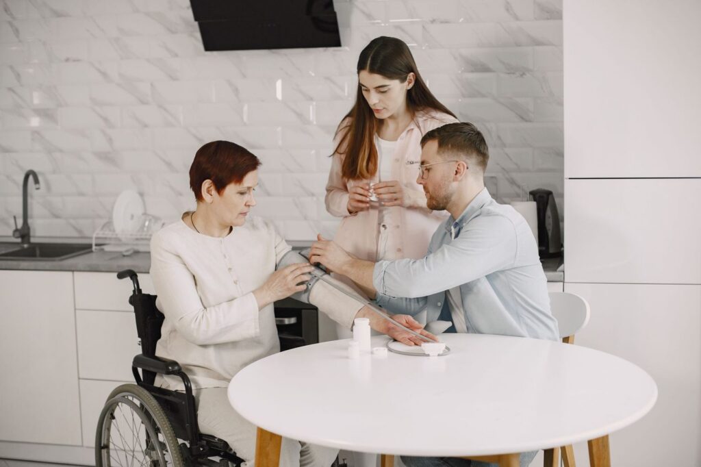 Family member checking blood pressure of person in wheelchair at home.