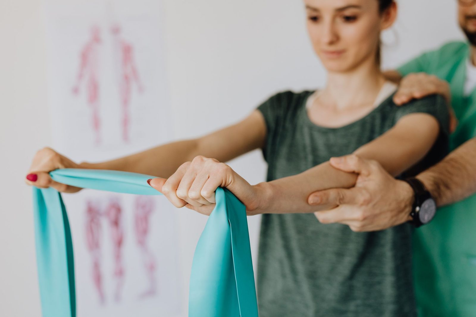 Orthopedist applying elastic tape to patient's arm in medical office.