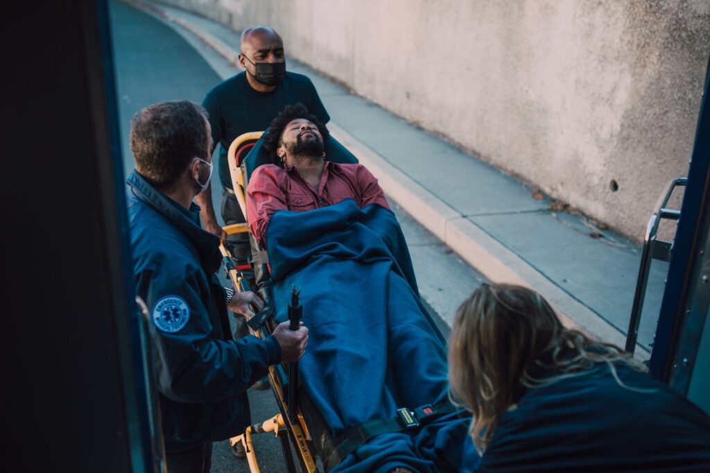 Paramedics loading an injured patient onto a stretcher during emergency response.
