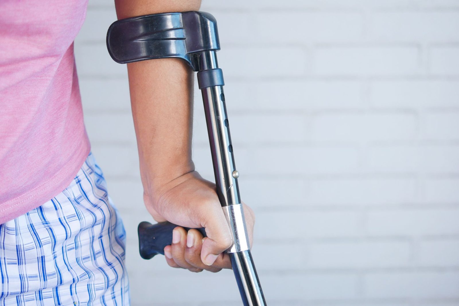 Person using crutch for mobility support indoors.