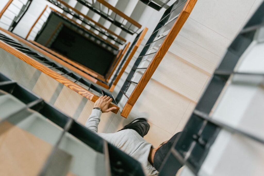 Person walking down stairs viewed from above, showing geometric staircase lines.