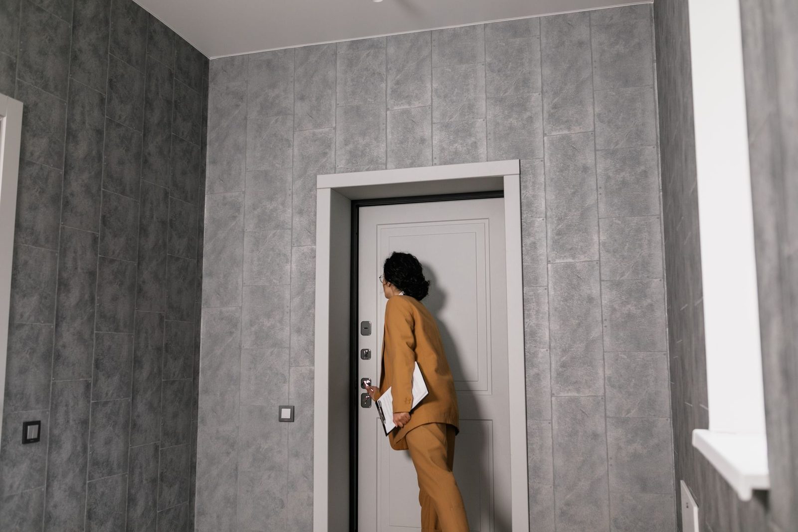 Real estate agent in business suit examining modern home entrance.