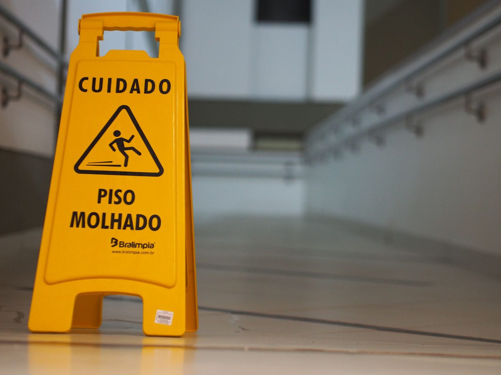 Señal amarilla de precaución por piso mojado en un pasillo interior.