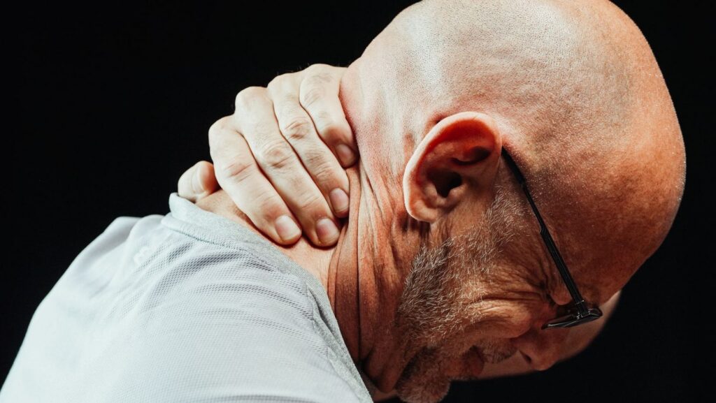 Senior man holding his neck in pain from injury.