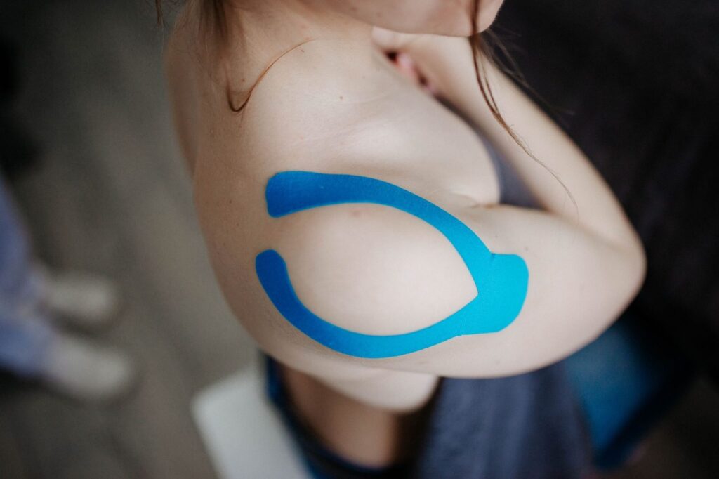 Shoulder with kinesiology tape applied for muscle support.