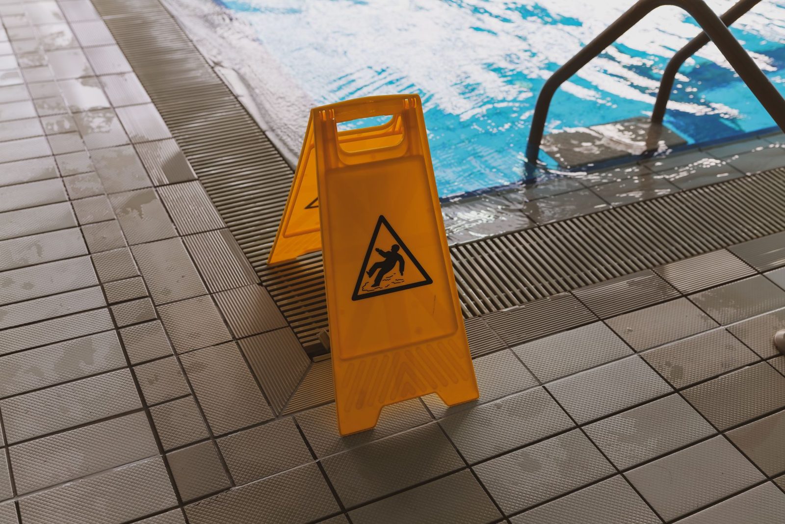 Wet floor caution sign beside a swimming pool.