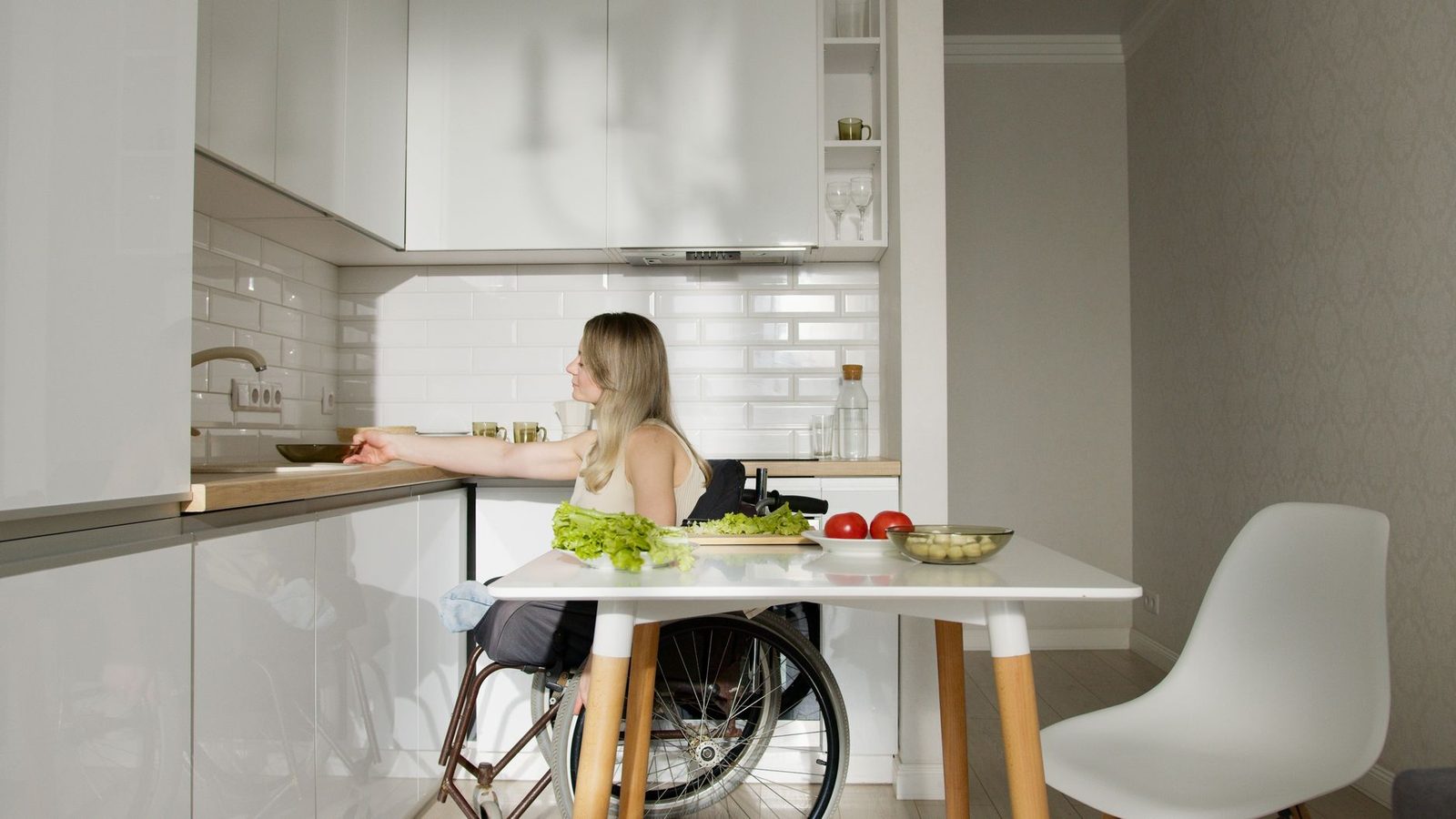 Woman in wheelchair preparing food at kitchen counter with fresh vegetables.