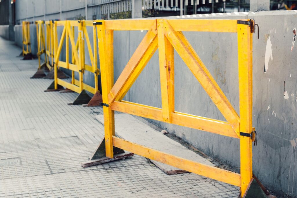 Yellow construction barriers blocking a sidewalk.