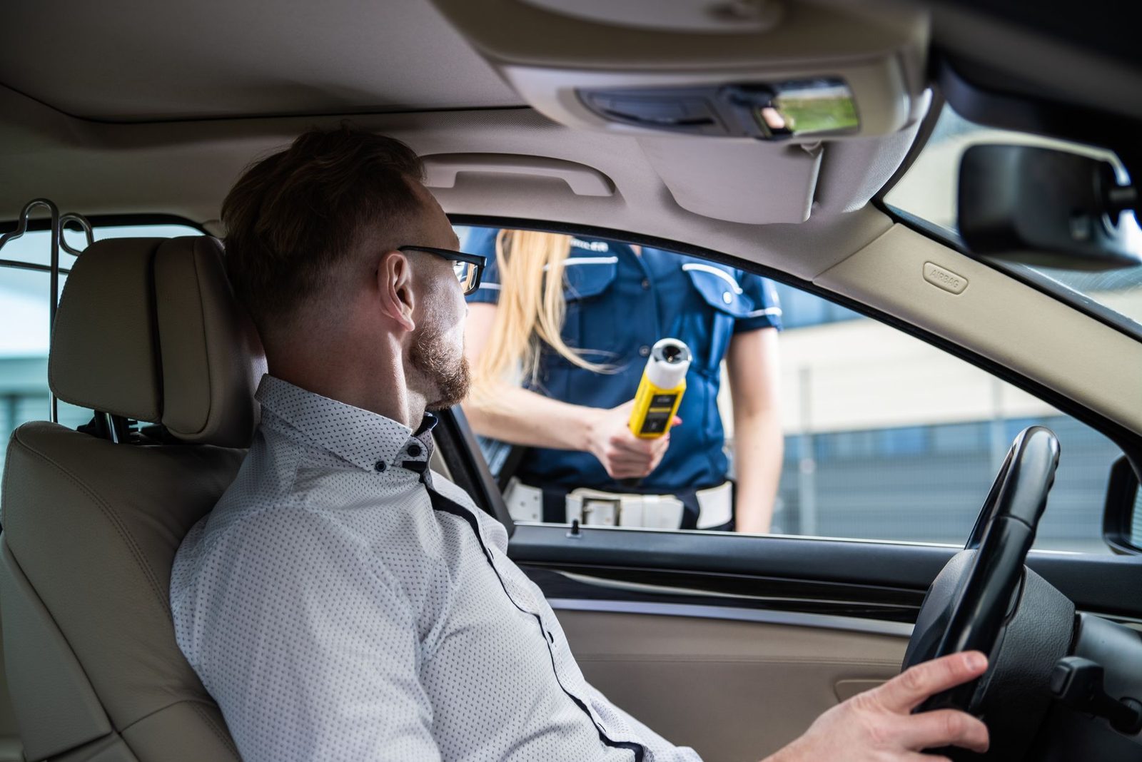 A police officer gives a driver a breathalyzer test at a roadside traffic stop.