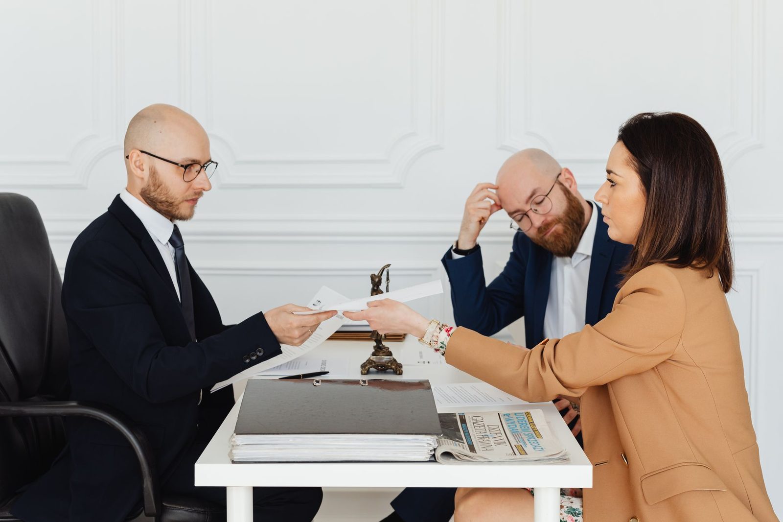 Abogado y clientes revisando documentos en oficina moderna durante reunión profesional.