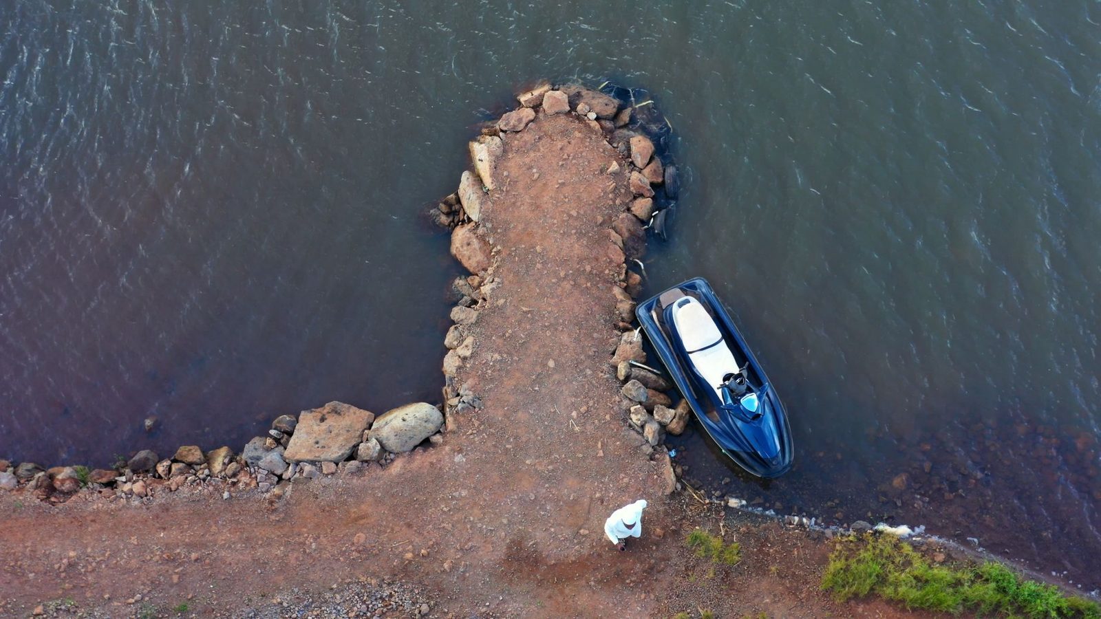 Aerial view of a jet ski parked at a rocky dock beside calm water.