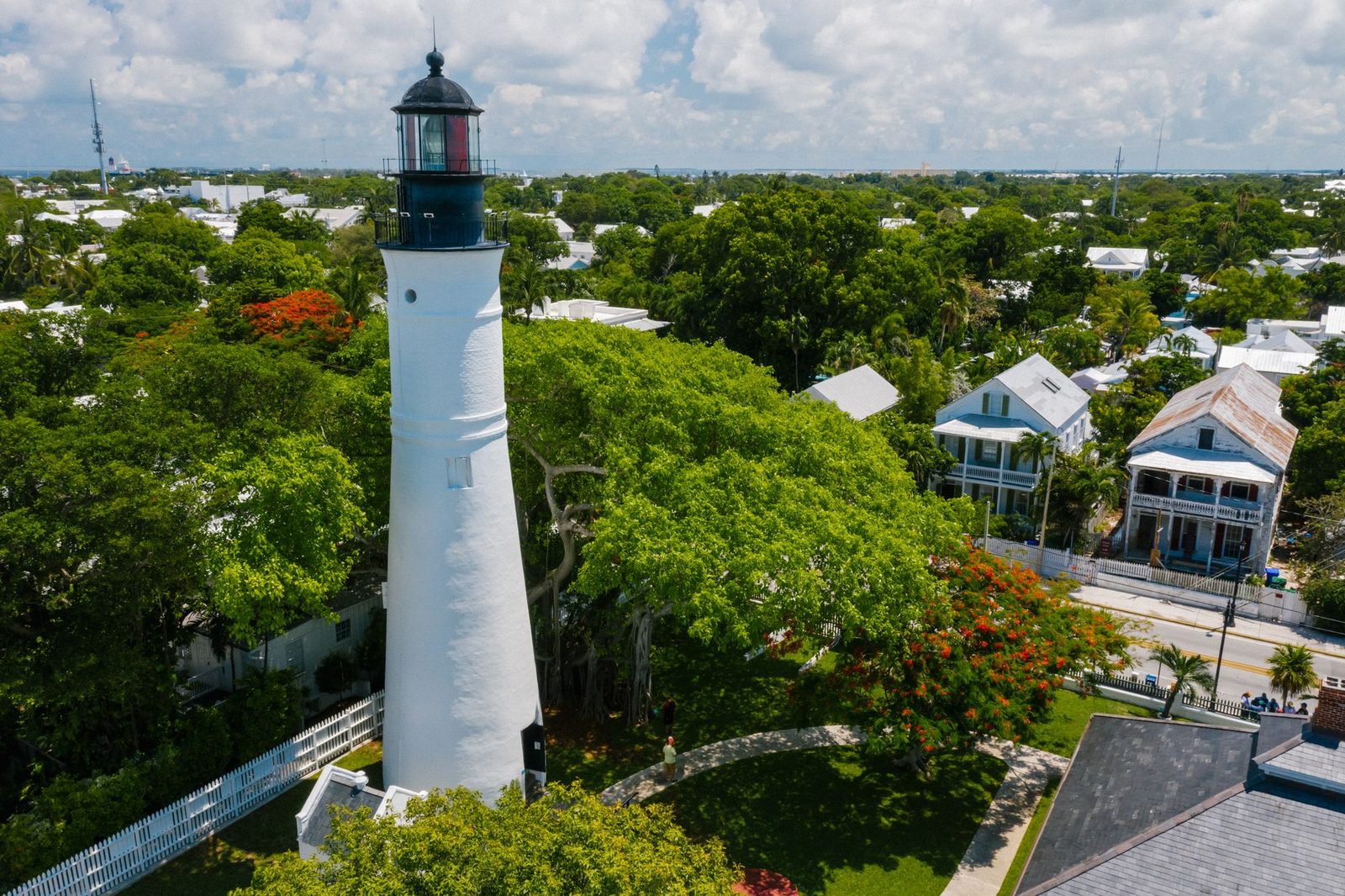 Vista aérea del faro de Key West, rodeado de árboles verdes y casas históricas.