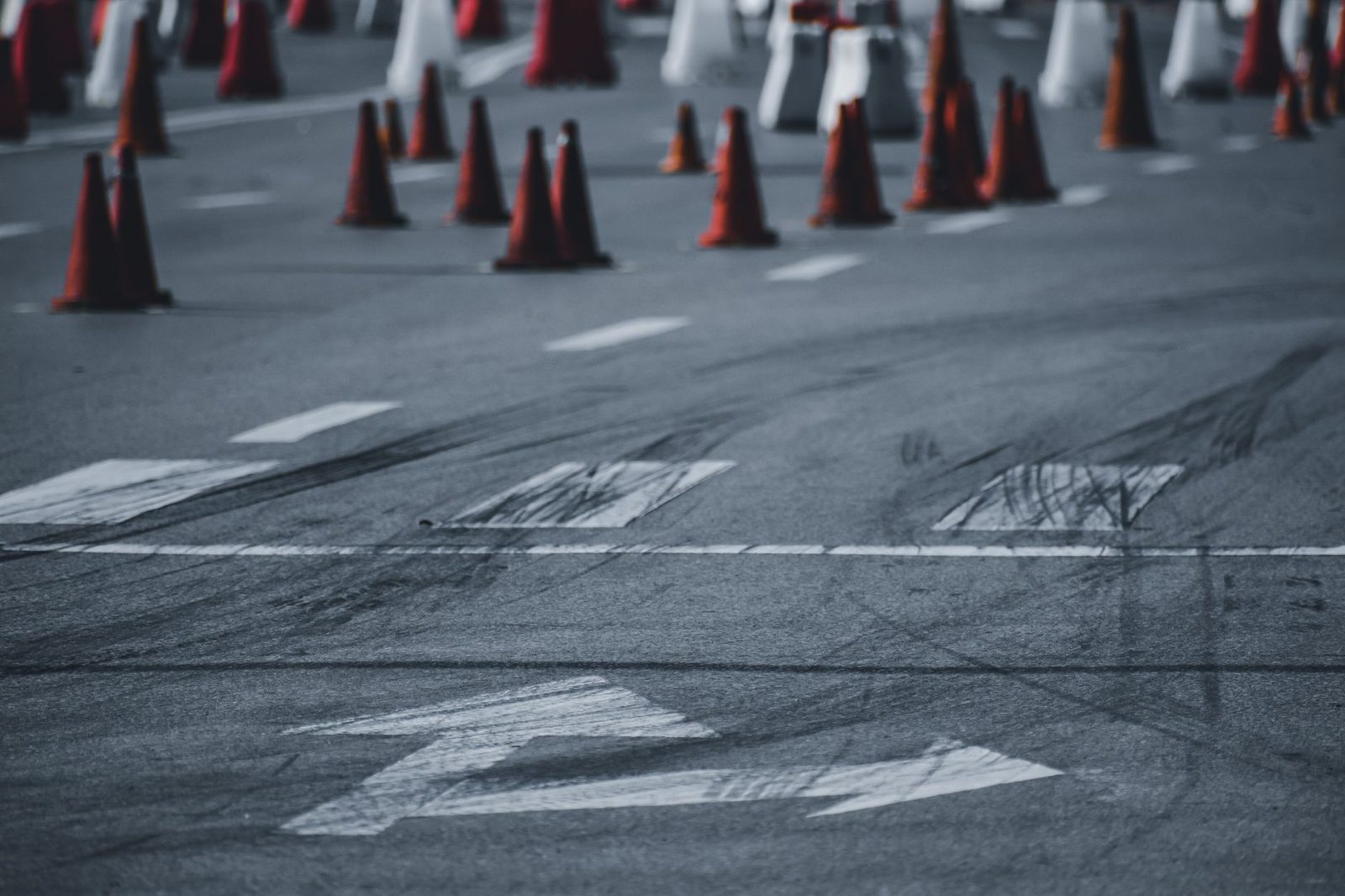 Asphalt road with black tire marks and red traffic cones marking an accident scene.