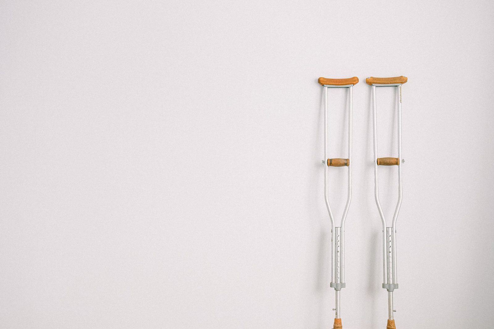 Crutches leaning against a white wall, representing mobility assistance after injury.