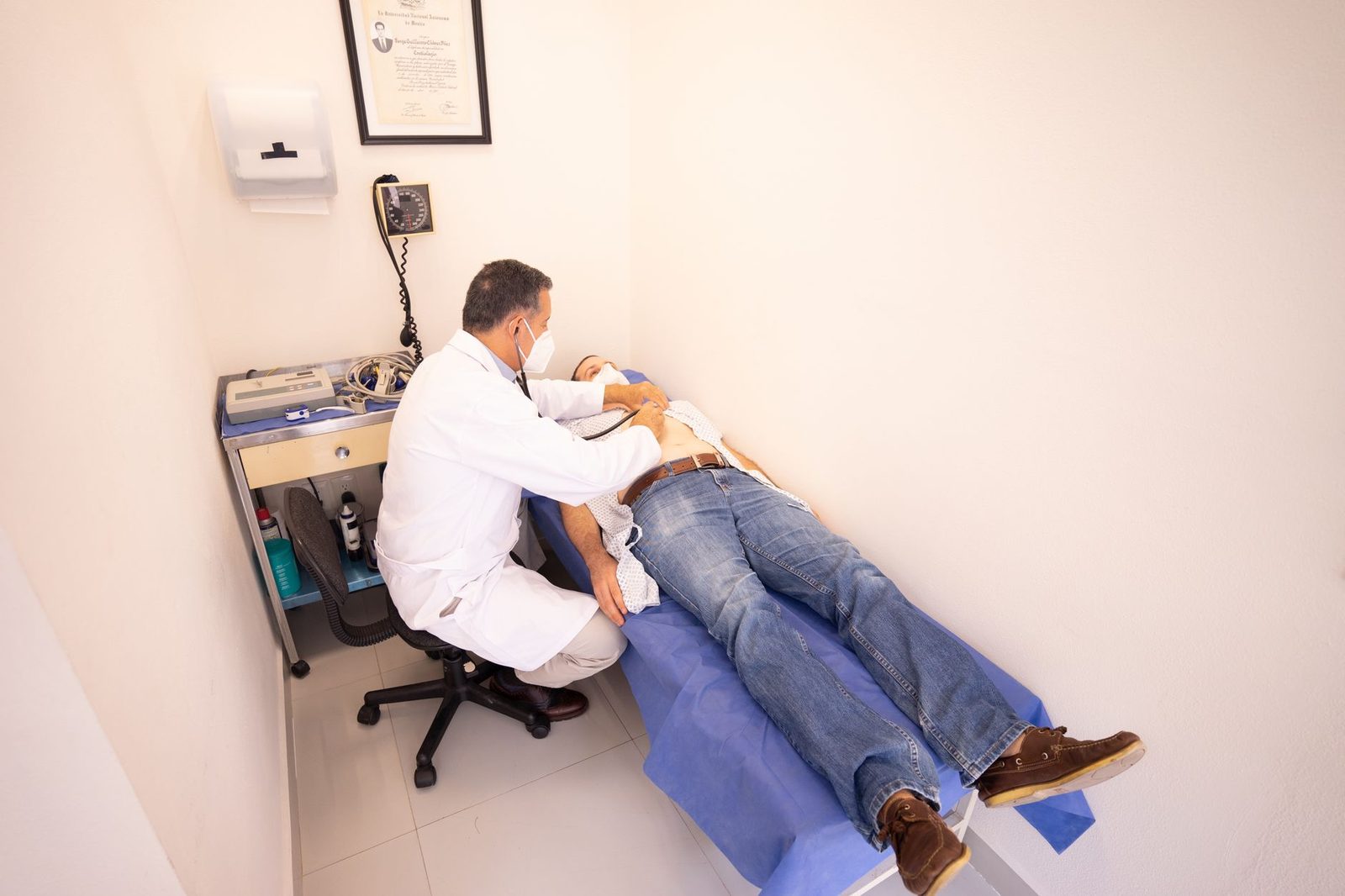 Médico examina a paciente con estetoscopio en consultorio clínico.