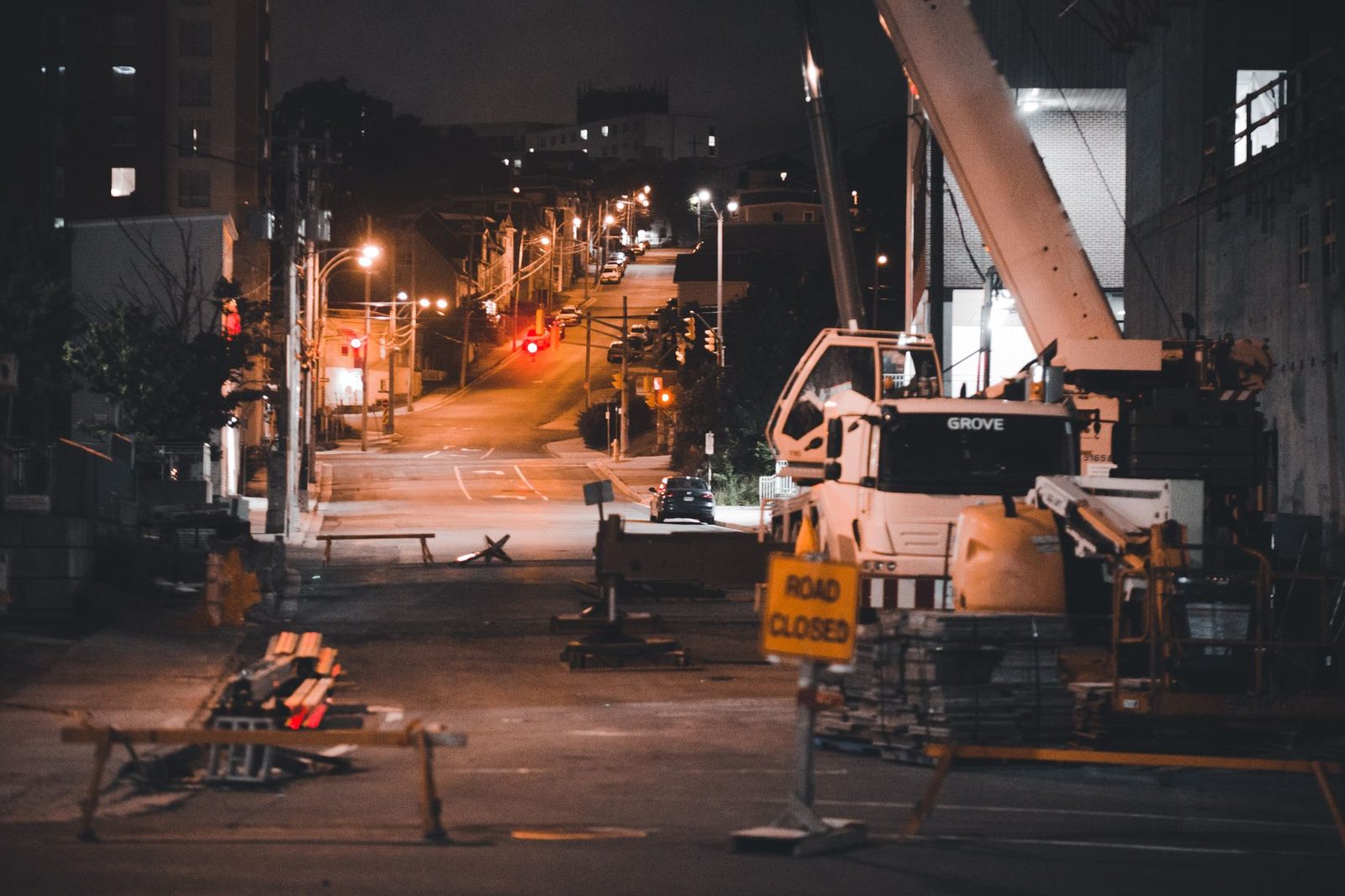 Quiet city street at night with construction equipment and a road closed sign.