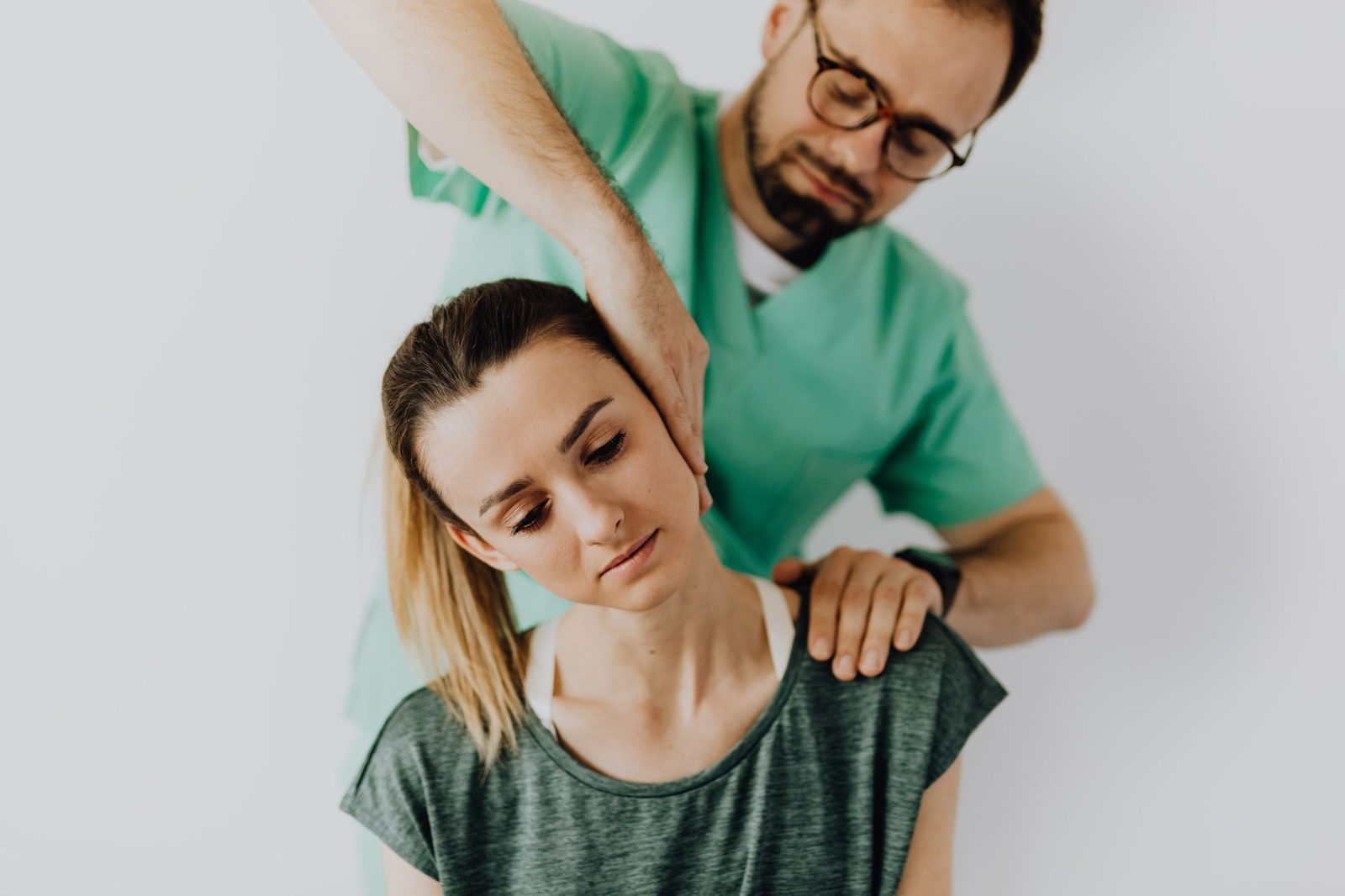 Terapeuta realizando masaje terapéutico de cuello a paciente en consultorio médico.