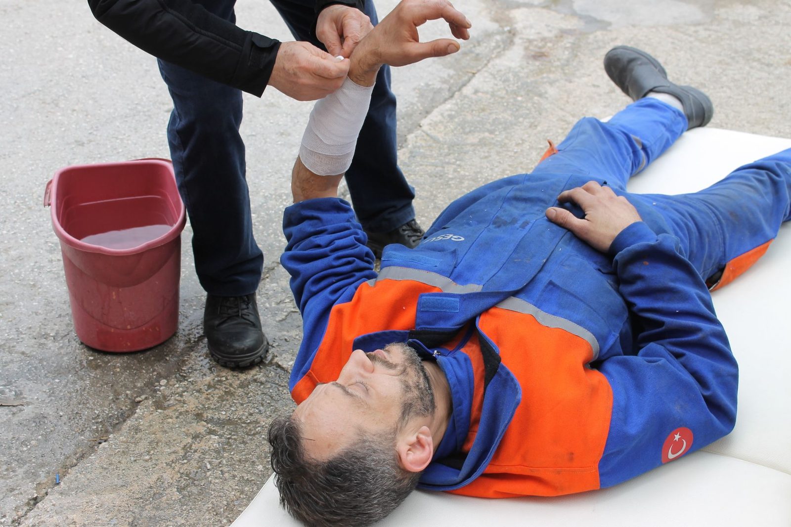 Trabajador lesionado recibiendo primeros auxilios en el sitio con vendaje en el brazo.