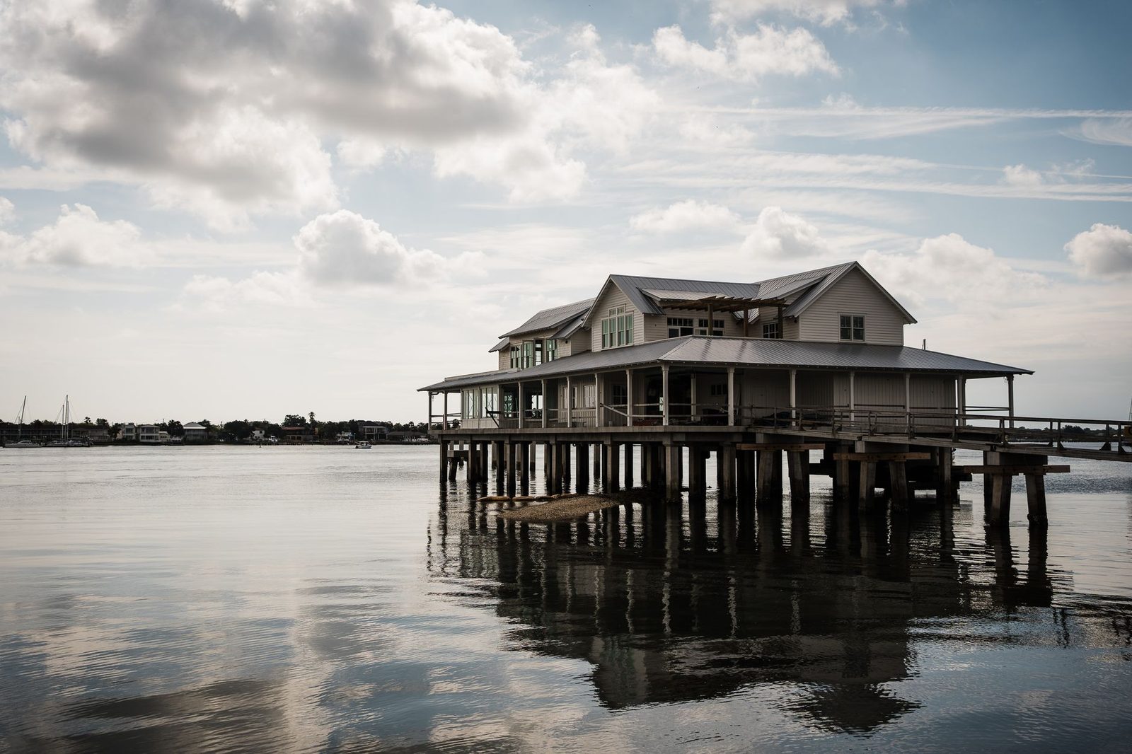 Waterfront house on stilts in St. Augustine, Florida, under a partly cloudy sky.