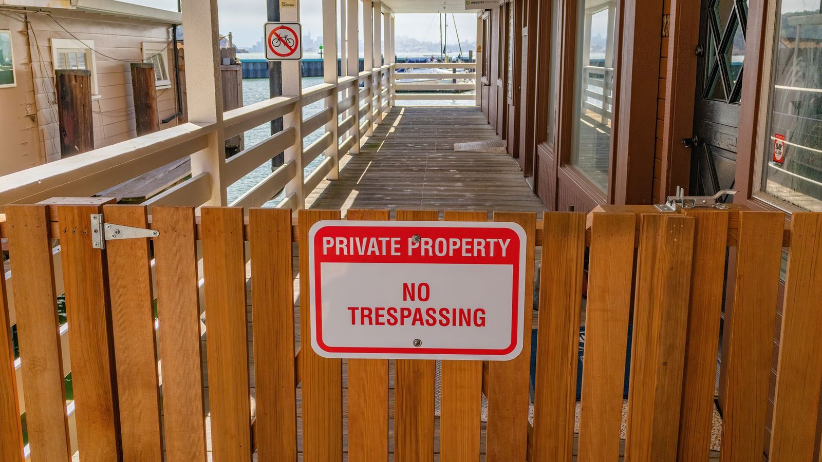 Wooden gate with "Private Property No Trespassing" sign on rural property.