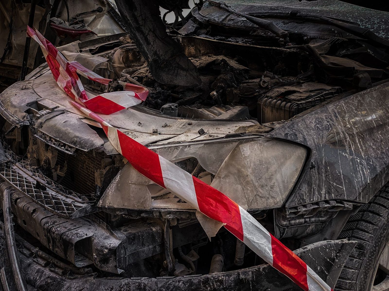 Wrecked car covered with yellow and black safety tape at accident scene.