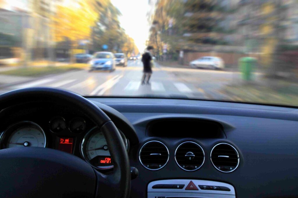 A man in front of a speedy car