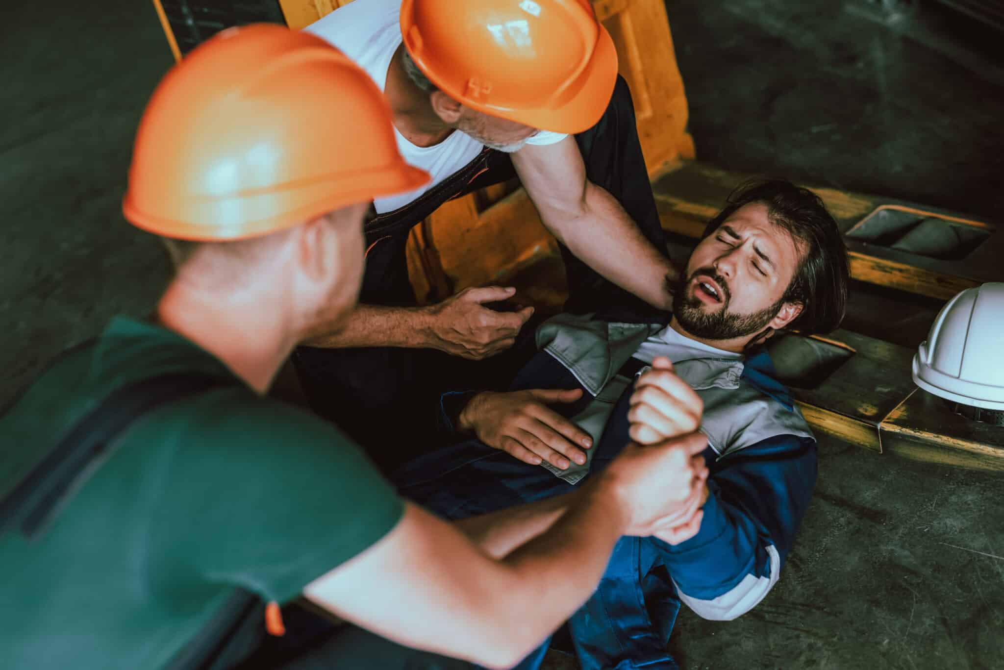 Workers in hard hats assisting an injured colleague