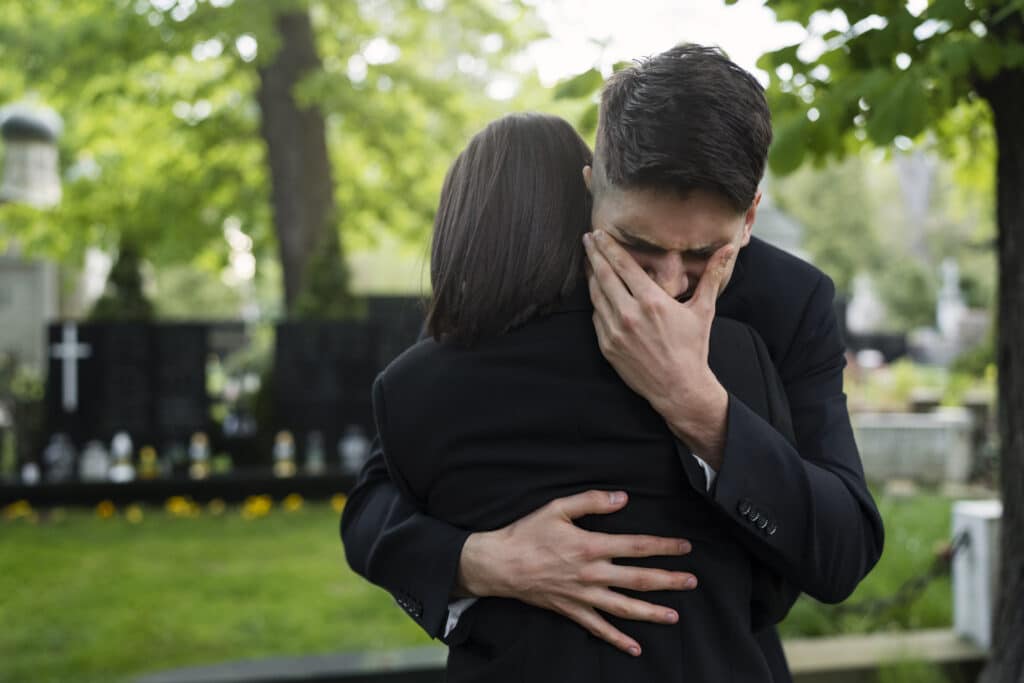 Embrace at a graveside showing grief and support